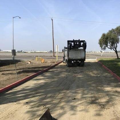 Construction workers cleaning asphalt and concrete after asphalt resurfacing project.